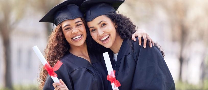 Two college programs graduates holding their diplomas.